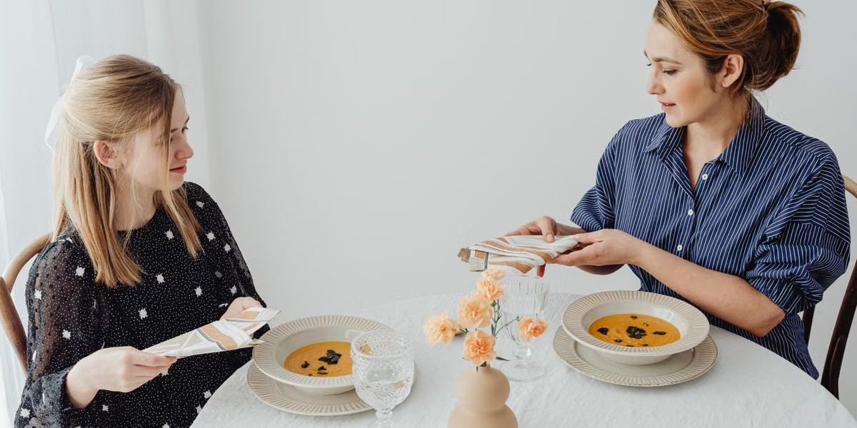 Two women dining with soup at an elegantly set table.